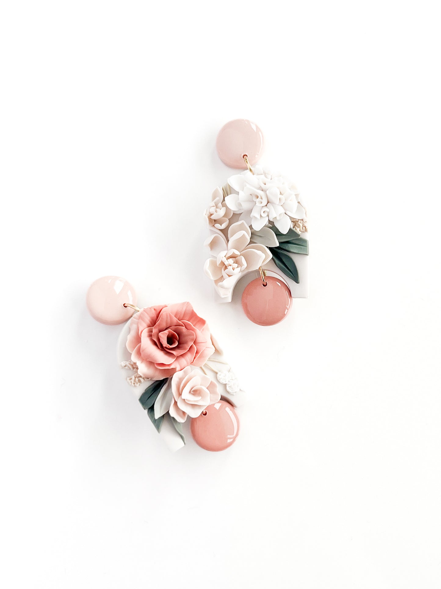Remi by Agave Designs: Handmade earrings with light pink circular studs, detailed pink, white, and green floral designs—roses and leaves—on a white base. Finished with sterling silver posts for a touch of elegance.