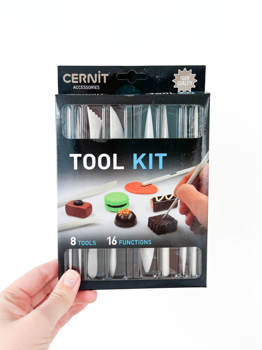 A hand holds a packaged Cernit Tool Kit from Agave Designs against a white background. The black box displays text "8 Tools, 16 Functions" and shows images of the precision modeling tools being used on small pieces of colored clay or fondant. "HIGH QUALITY" is printed at the top right corner.