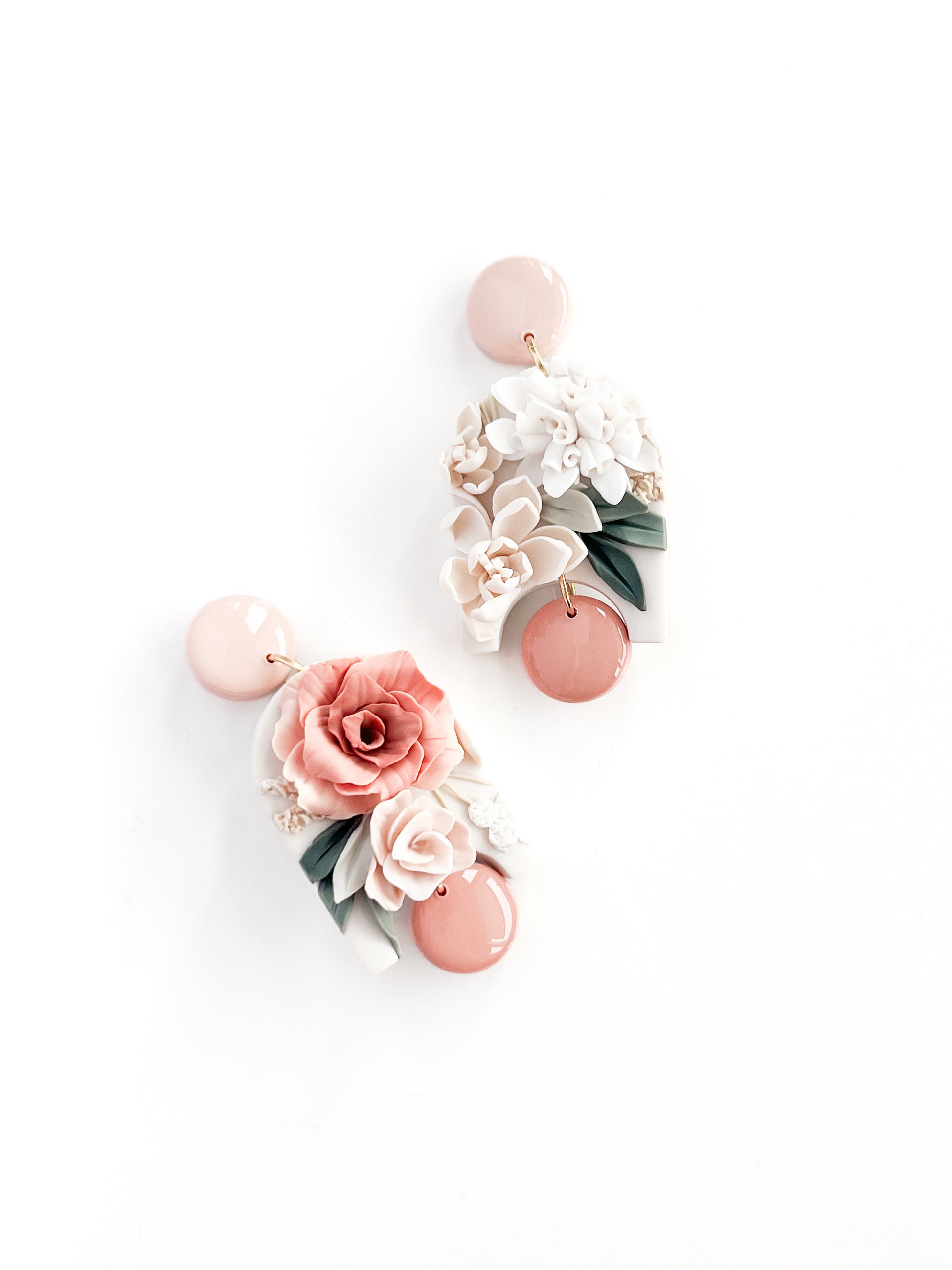 Remi by Agave Designs: Handmade earrings with light pink circular studs, detailed pink, white, and green floral designs—roses and leaves—on a white base. Finished with sterling silver posts for a touch of elegance.